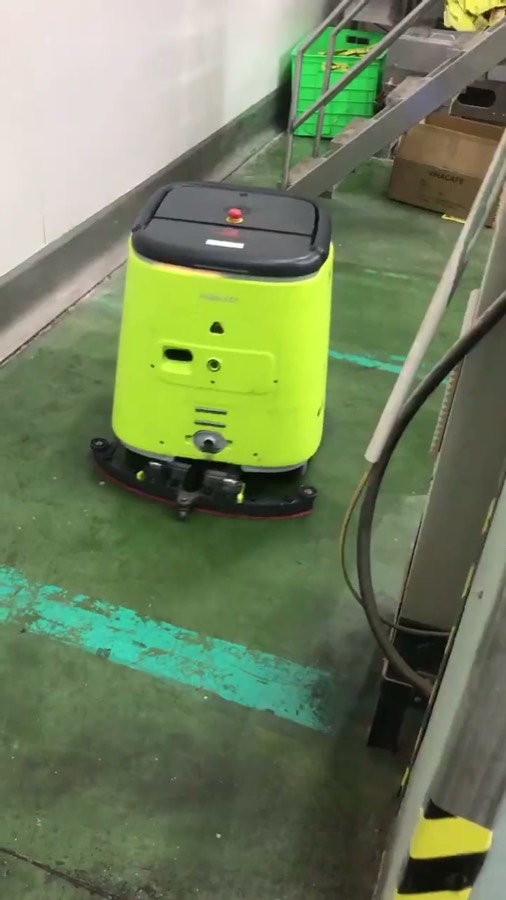 Robot CC1 trong lối đi hẹp cạnh cầu thang sắt có lan can, dây cáp vắt trên sàn